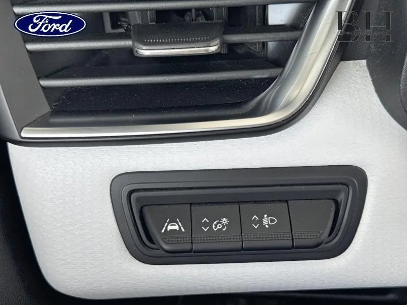 Gros plan sur les commandes d'assistance à la conduite sur tableau de bord blanc d'une Renault Clio 2023.