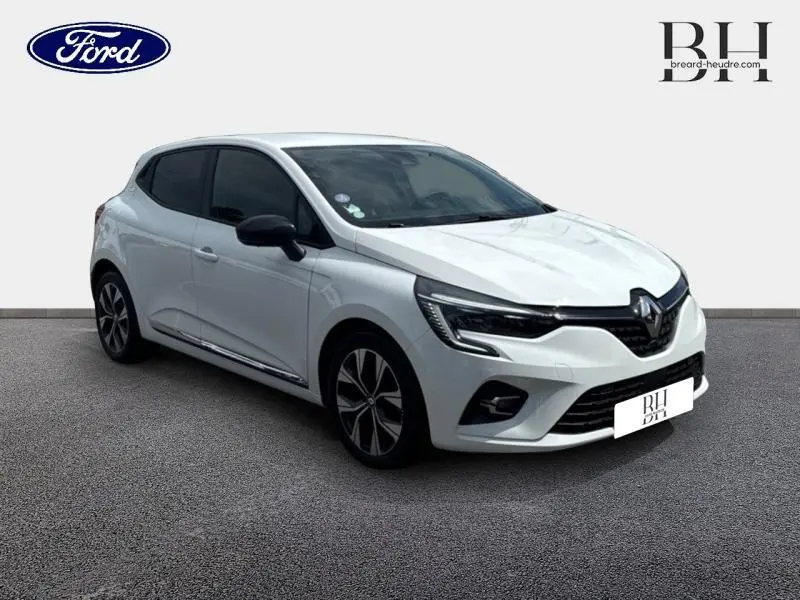 Renault Clio blanc glacier vue 3/4 avant droit avec vitres arrière surteintées et jantes alliage.
