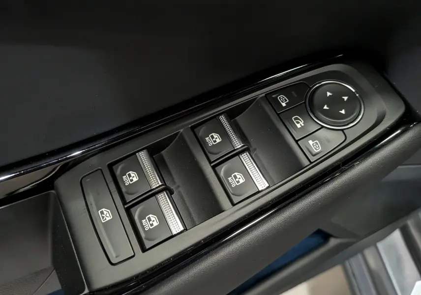 Gros plan sur les commandes de lève-vitres et rétroviseurs électriques noires sur la porte intérieure d'une Renault Rafale gris schiste.