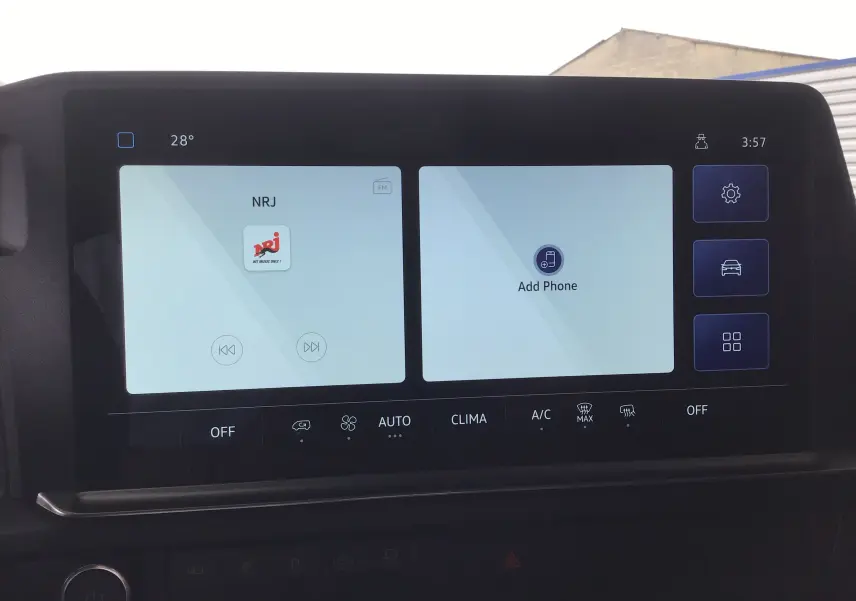 Écran tactile central du Volkswagen Transporter T7 2025 affichant la radio NRJ et l'option ajout téléphone.