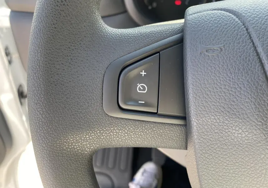 Gros plan sur le volant noir du Nissan Interstar blanc 2022, montrant les commandes de régulateur de vitesse.
