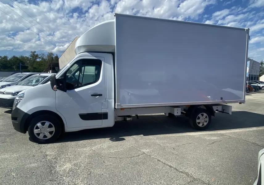 Profil droit d'un utilitaire blanc Nissan Interstar 2022 avec caisse grand volume et capucine sur parking.