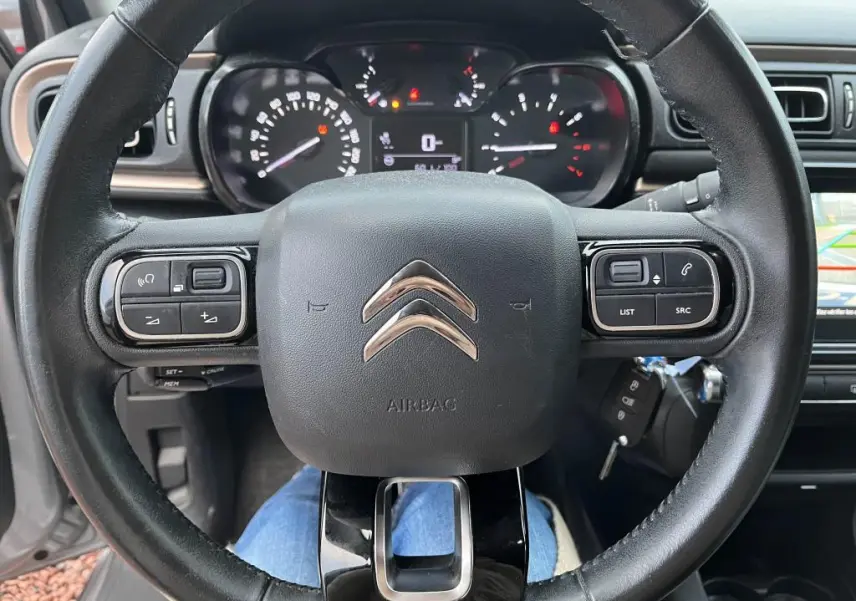 Vue rapprochée du volant Citroën C3 2019 avec commandes intégrées et tableau de bord numérique allumé.