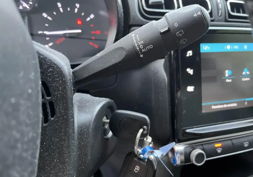 Gros plan sur la commande d'essuie-glace et le tableau de bord numérique d'une Citroën C3 gris foncé de 2019.