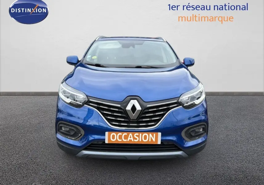 Vue avant d'un Renault Kadjar bleu Iron 2021 avec calandre chromée et phares LED allumés.