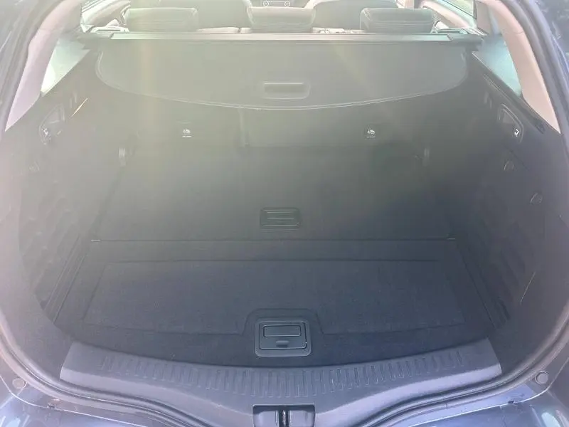 Vue du coffre ouvert de la Renault Mégane Break gris Titanium 2024, montrant un espace de chargement propre et spacieux.