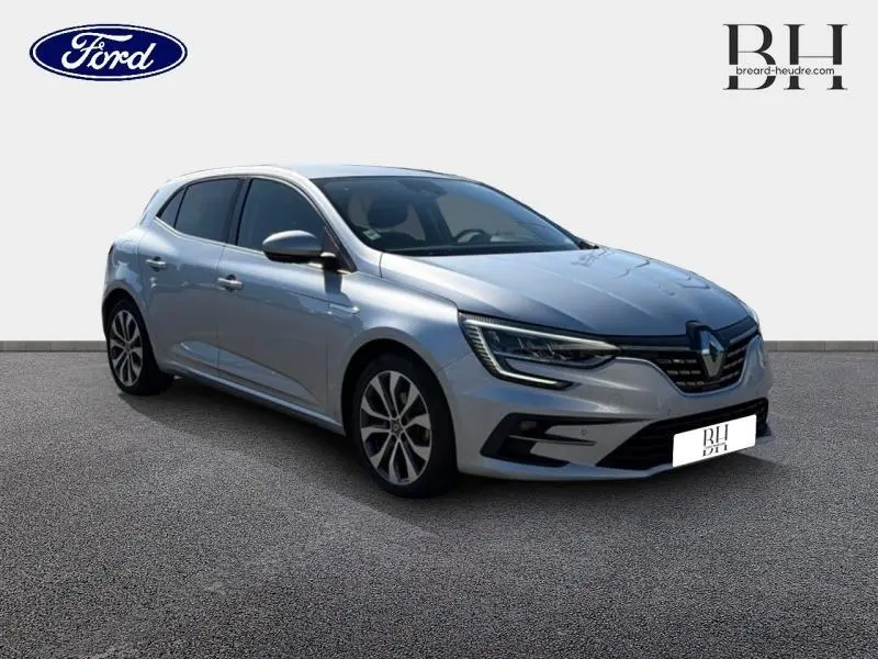 Vue 3/4 avant droite d'une Renault Mégane gris Highland 2023 avec phares LED et jantes alliage.