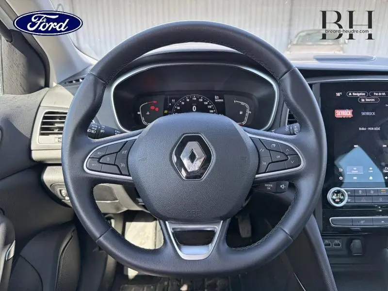 Vue centrée sur le volant noir de la Renault Mégane 1.5 Blue dCi 115ch Techno 2023 avec tableau de bord numérique et écran tactile.