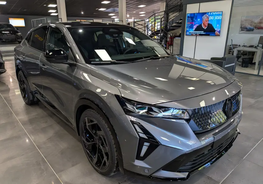 Vue 3/4 avant droit du Renault Rafale gris schiste avec calandre noire et jantes noires en showroom.