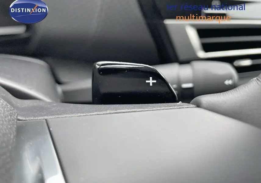 Gros plan sur la palette de changement de vitesse "+" côté droit du volant d'une Citroën C4 blanche métal 2024.