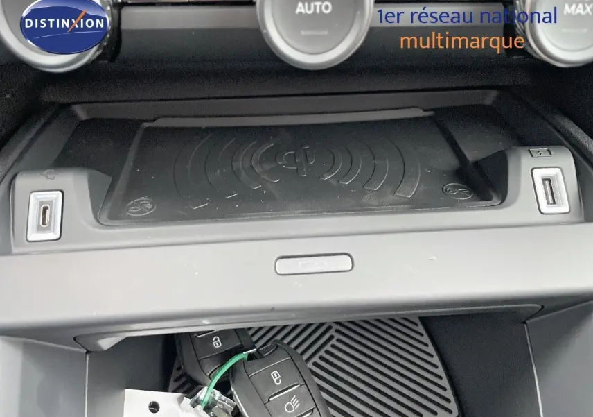 Gros plan sur la console centrale de la Citroën C4 blanche, montrant le chargeur sans fil et deux clés de voiture.