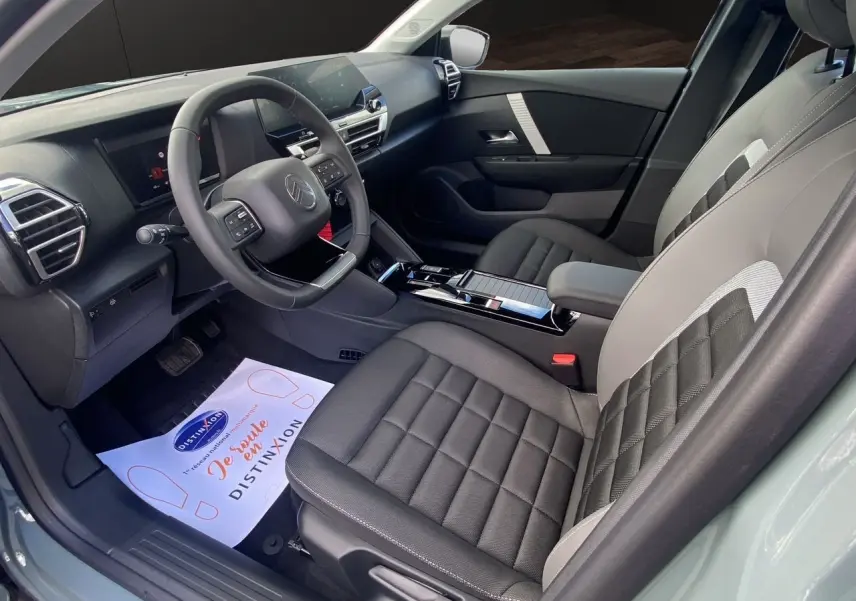 Intérieur avant droit de la Citroën C4 2025 Manhattan Green, sièges tissu noir et gris, tableau de bord moderne avec écran tactile.