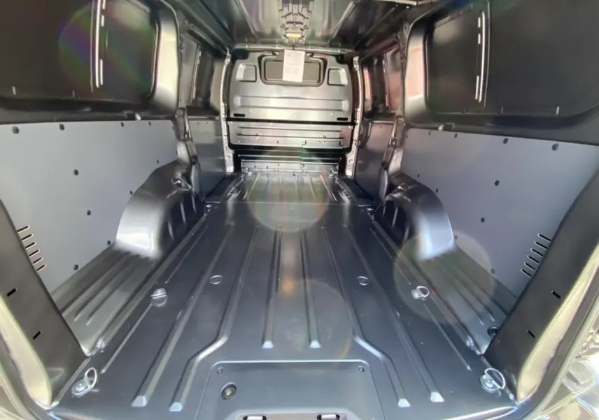 Vue intérieure du coffre du Peugeot Expert Fourgon gris platinium, montrant l'espace de chargement tôlé et les renforts latéraux.