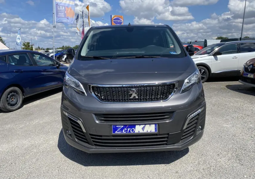 Vue de face d'un Peugeot Expert Fourgon gris platinium 2022 avec calandre noire et plaque Zero KM visible.