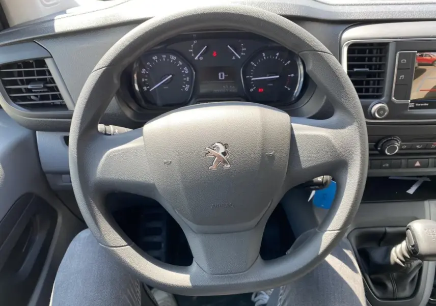 Vue intérieure centrée sur le volant Peugeot du Expert Fourgon gris platinium avec tableau de bord et levier de vitesse manuel.