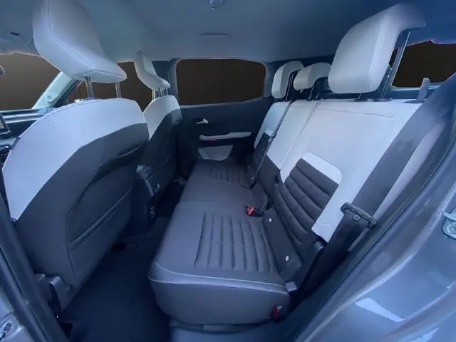 Vue intérieure arrière droite du Citroën C3 Aircross Hybrid 145 gris Mercury, sièges tissu noir et blanc contrastés.
