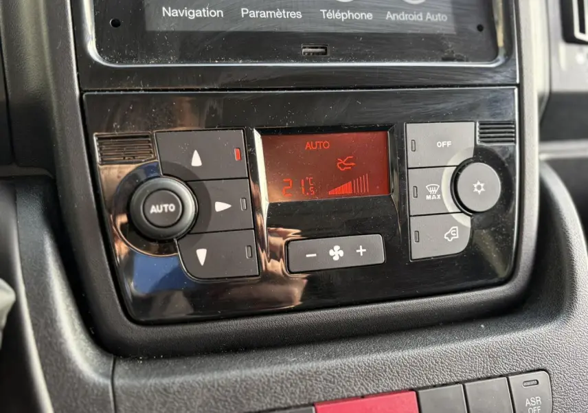 Gros plan sur la commande de climatisation automatique avec écran digital rouge dans l’habitacle de l’Opel Movano Fourgon blanc.