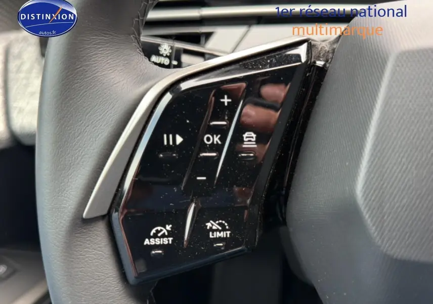 Gros plan sur les commandes multifonctions noires du volant cuir côté gauche du Peugeot 5008 Hybrid 145 allure e-dcs6 noir.