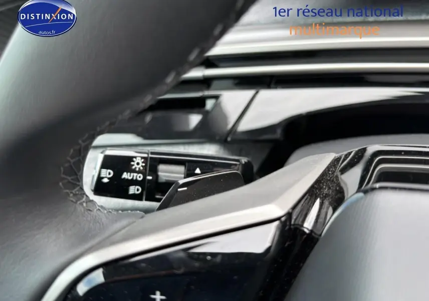 Gros plan sur le volant cuir noir et la commande des phares automatiques du Peugeot 5008 Hybrid 145 allure e-dcs6 2025.