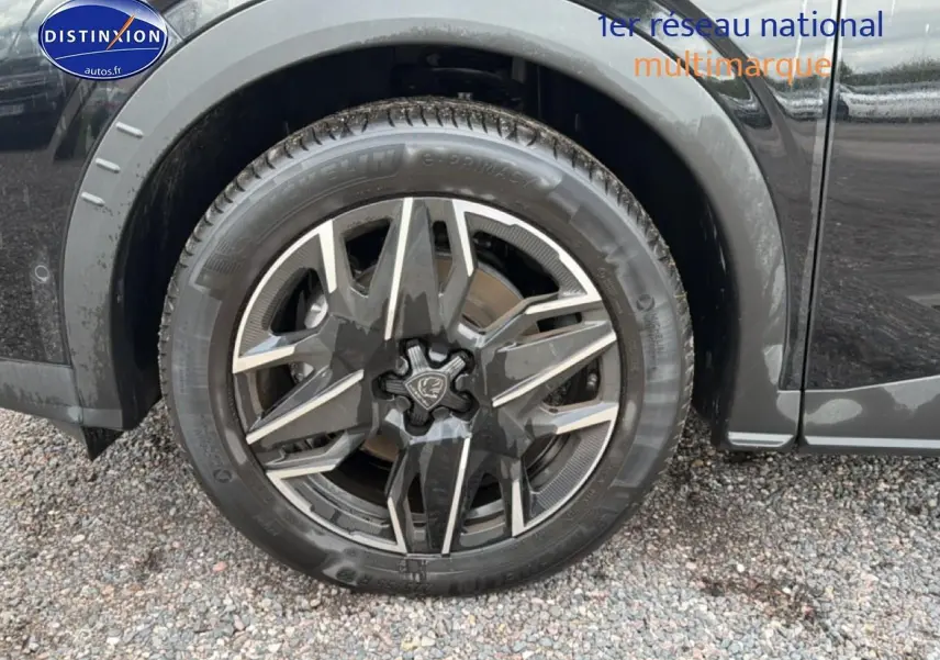Gros plan sur la roue avant gauche noire du Peugeot 5008 Hybrid 145 allure e-dcs6 avec jante alu distinctive.