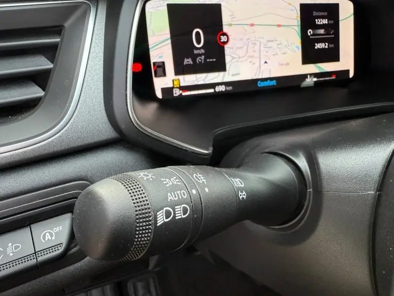 Gros plan sur la commande des feux du tableau de bord du Renault Captur 2025, avec affichage numérique en arrière-plan.