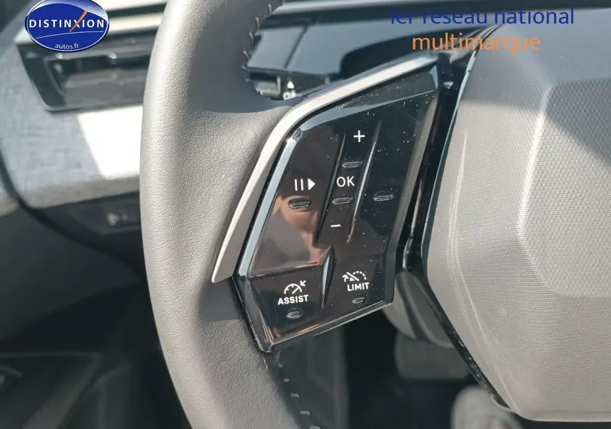 Gros plan sur les commandes au volant cuir noir du Peugeot 5008 gris artense, mettant en valeur les boutons multifonctions.