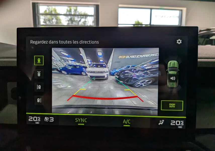 Écran de caméra de recul affichant un Dacia Bigster noir nacré vu de face dans un parking intérieur.