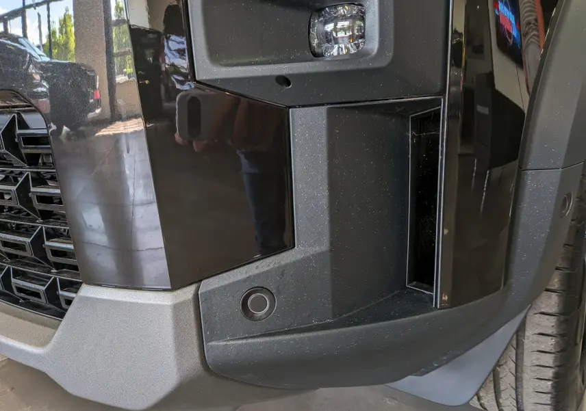 Gros plan sur l’angle avant droit du pare-chocs noir nacré du Dacia Bigster 2026 avec capteur de stationnement visible.