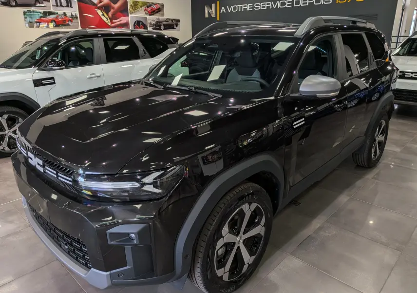 Vue 3/4 avant droite du Dacia Bigster noir nacré 2026 en showroom, soulignant ses jantes distinctives et ses lignes modernes.