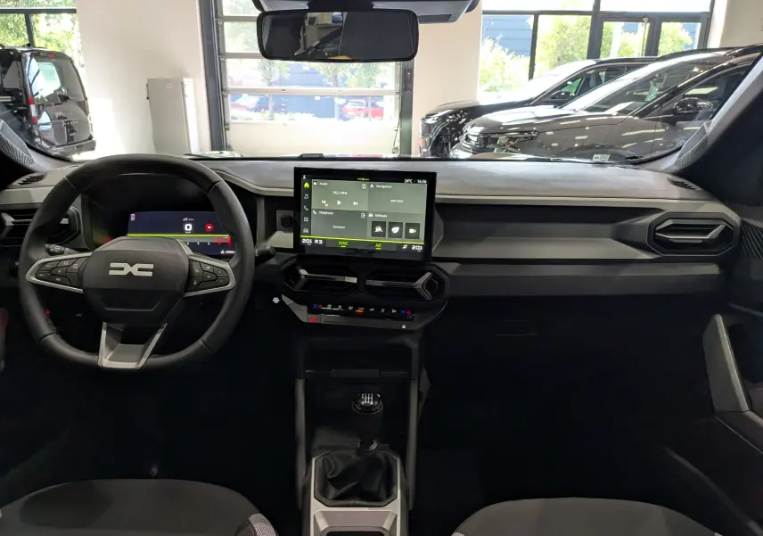 Vue intérieure avant du tableau de bord noir du Dacia Bigster Mild Hybrid avec écran tactile et volant multifonction.