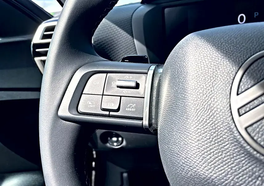 Gros plan sur le volant cuir noir de la Citroën C4 X 2025, avec commandes intégrées côté gauche visibles.