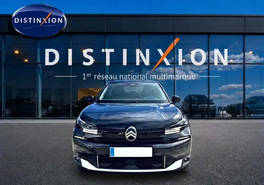 Vue avant d'une Citroën C4 X noire 2025, avec logo distinctif et phares LED fins, devant une vitrine Distinxion.