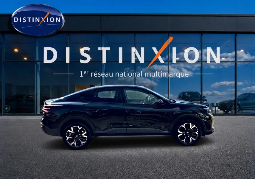 Profil droit de la Citroën C4 X hybride noire 2025, avec jantes alu et lignes fluides devant un showroom Distinxion.