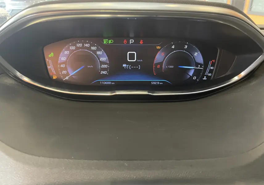 Tableau de bord numérique du Peugeot 5008 blanc nacré, affichant vitesse, compte-tours et indicateurs en vue frontale.