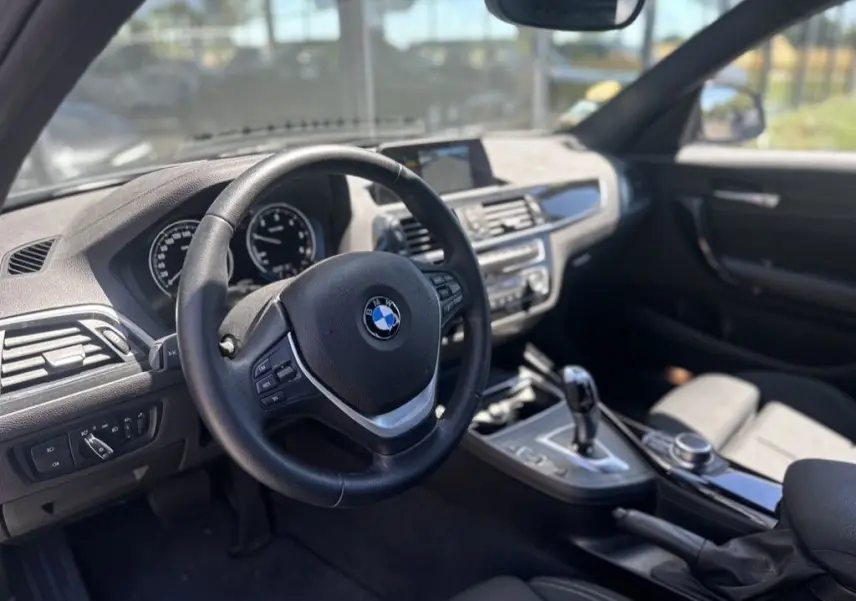 Vue intérieure de la BMW Série 1 F20 116d 2019, montrant le volant, tableau de bord et console centrale en noir.