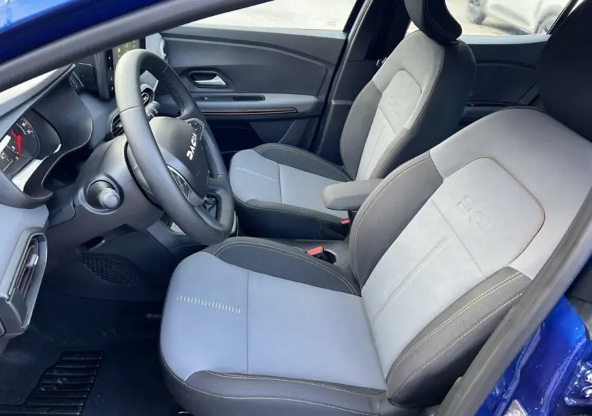Intérieur de la Dacia Sandero Stepway 2024 en bleu iron, vue côté conducteur montrant sièges bi-ton et volant multifonction.