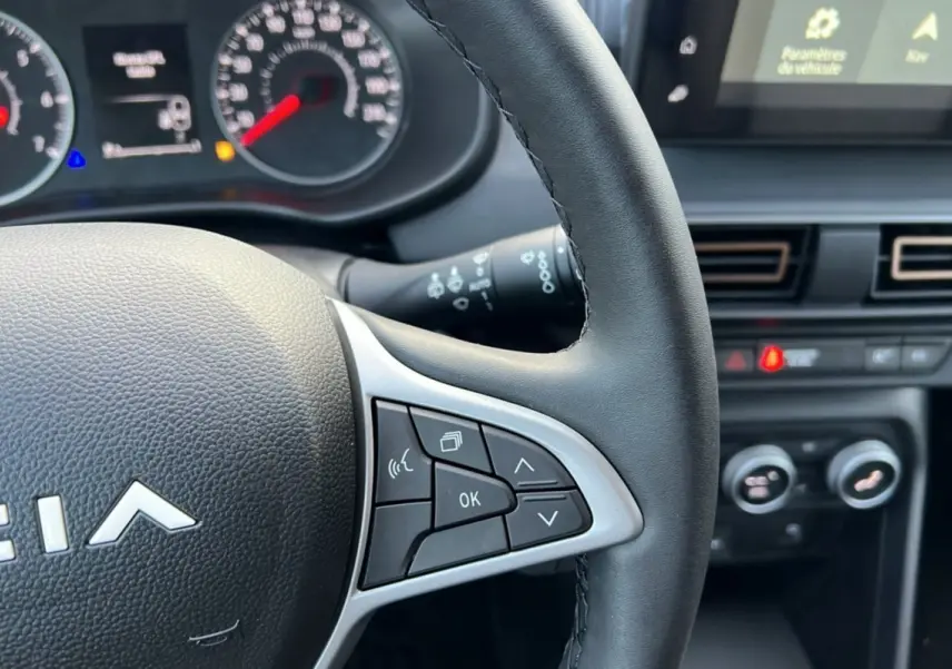 Gros plan sur le volant et le tableau de bord du Dacia Sandero Stepway Bleu iron 2024, avec commandes multifonctions visibles.