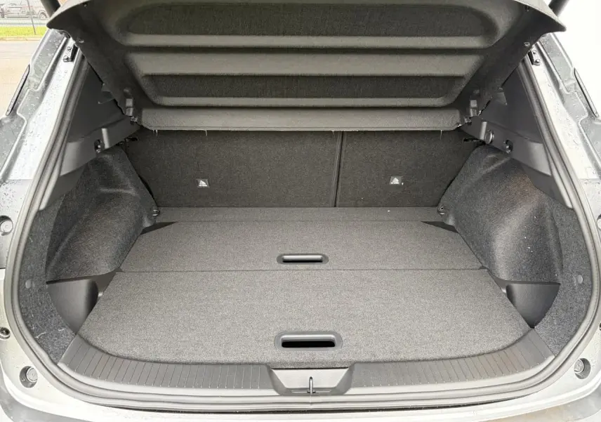 Coffre ouvert du Nissan Qashqai III 2025 gris foncé, vue arrière montrant un espace de chargement plat et doublé.