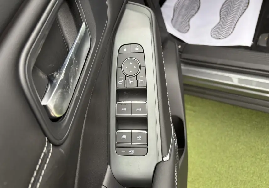 Vue rapprochée du panneau de commandes des vitres et rétroviseurs côté conducteur du Nissan Qashqai gris foncé.