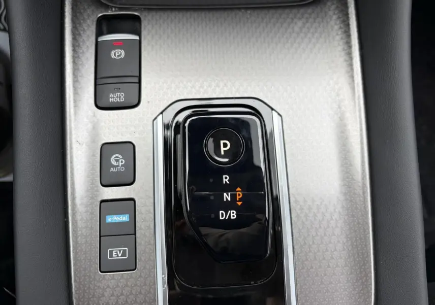 Vue rapprochée de la console centrale grise avec sélecteur de boîte auto et boutons de contrôle du Nissan Qashqai hybride.