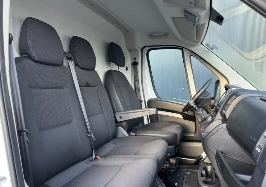 Vue intérieure côté conducteur de l'Opel Movano Fourgon 2024 avec sièges noirs et tableau de bord visible.