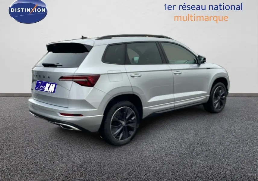 Vue 3/4 arrière droite d'un Skoda Karoq gris argent métallisé avec jantes noires et toit ouvrant.