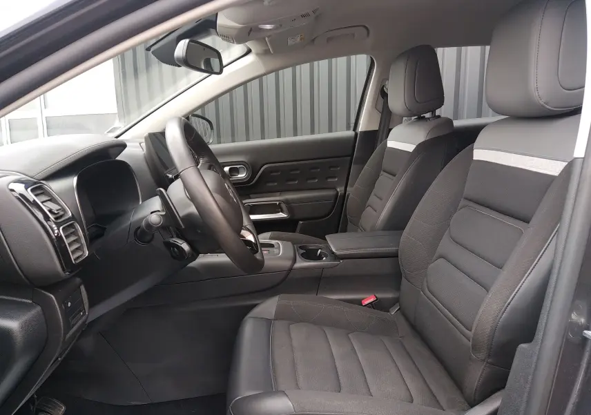 Vue intérieure côté conducteur du Citroën C5 Aircross 2023, sièges tissu noir avec détails gris et tableau de bord moderne.