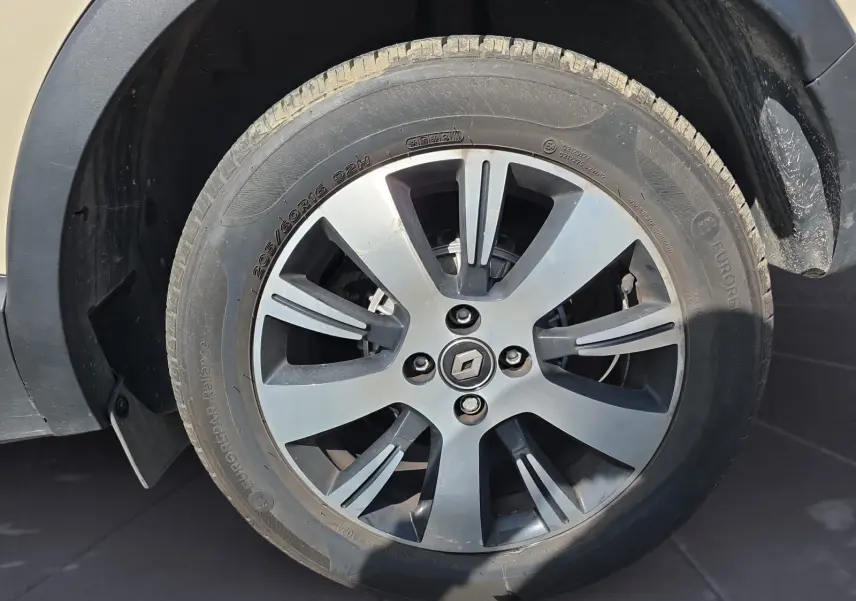 Gros plan sur la roue avant gauche d’un Renault Captur ivoire, mettant en valeur la jante alliage 16 pouces avec logo Renault central.