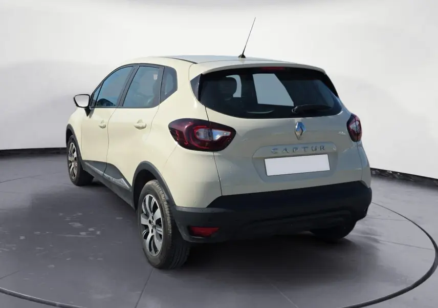 Vue 3/4 arrière droite d’un Renault Captur ivoire 2018 avec jantes alliage et détails noirs sur le bouclier.