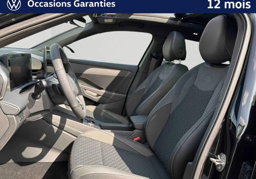 Vue intérieure côté conducteur du Volkswagen T-Roc noir 2026, sièges sport avec logo R et toit ouvrant panoramique visible.