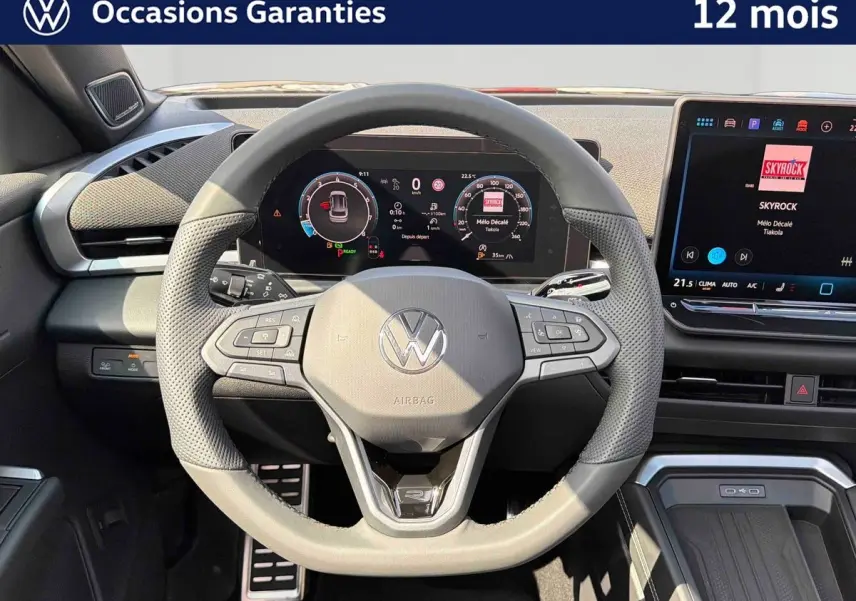 Vue frontale du volant noir perforé et du tableau de bord numérique du Volkswagen T-Roc 2026 avec écran tactile central.