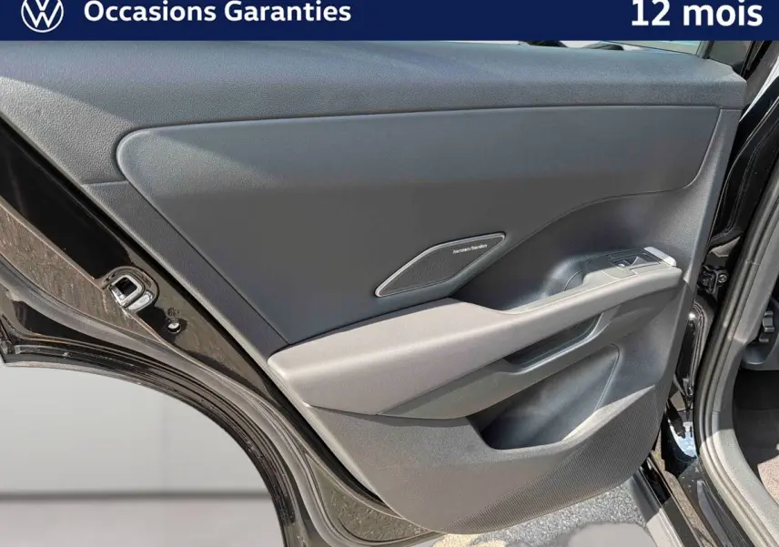 Vue rapprochée de la porte arrière droite noire du Volkswagen T-Roc 2026 avec haut-parleur Harman Kardon intégré.