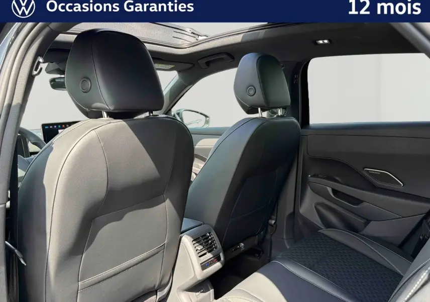 Vue arrière intérieure du Volkswagen T-Roc noir 2026, sièges en cuir, toit ouvrant panoramique et aérateurs arrière visibles.