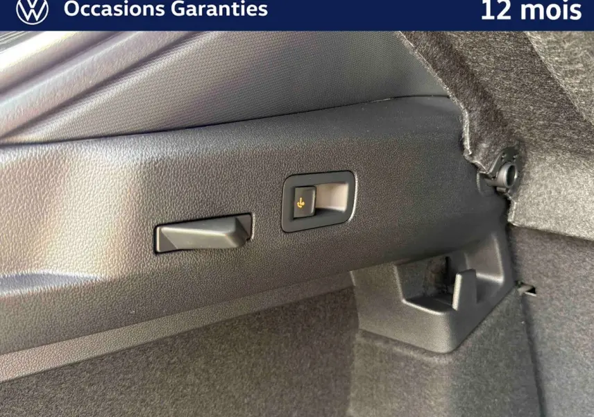Détail du coffre du Volkswagen T-Roc noir montrant le crochet d'attelage escamotable avec déverrouillage électrique.